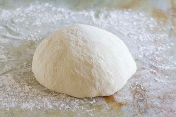 خمیر پیتزا آماده روی سطح آردپاشی شده