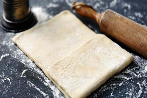 خمیر هزارلا روی سطح کار با وردنه برای تهیه بورک