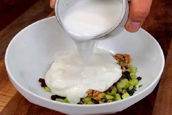 ریختن ماست روی مواد برای طرز تهیه آب دوغ خیار
