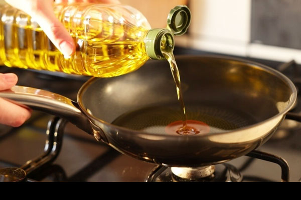ریختن روغن در تابه برای سرخ کردن جوجه چینی 