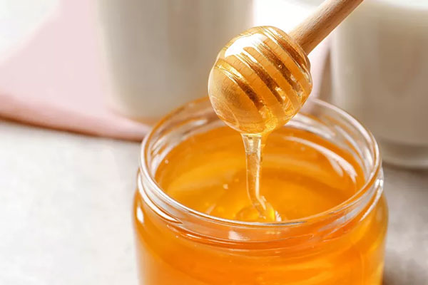 عسل در شیشه همراه با قاشق چوبی 