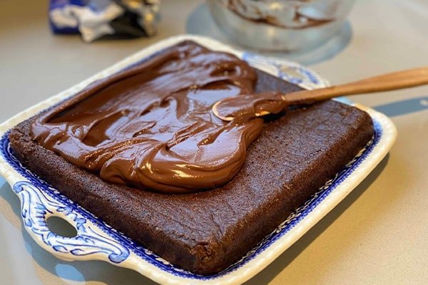 مالیدن سس شکلاتی روی کیک برای طرز تهیه کیک شکلاتی تولد