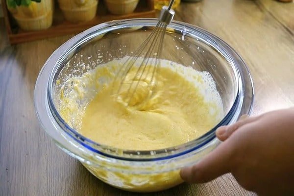 مخلوط کردن آرد و تخم‌مرغ در طرز تهیه کیک زعفرانی