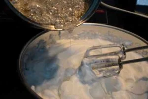 افزودن شربت به سفیده در طرز تهیه خامه کیک با سفیده تخمه مرغ