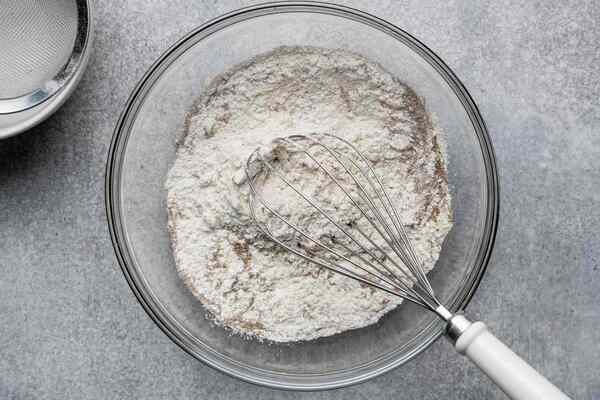 مخلوط کردن آرد با دیگر مواد در طرز تهیه کیک یزدی با شیر