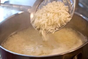آبکش کردن برنج برای تهیه عدس پلو ساده برای 4 نفر