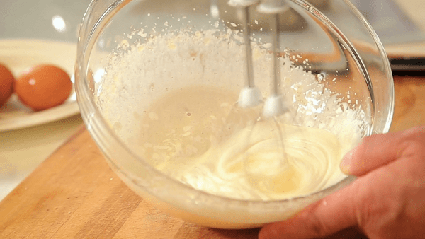 مخلوط کردن تخم‌مرغ و شکر در تهیه کیک یزدی