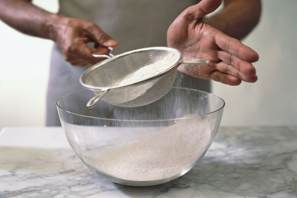 الک کردن آرد و بیکینگ پودر برای تهیه کیک یزدی