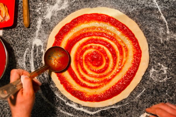 پهن کردن سس روی خمیر پیتزا گیاهی