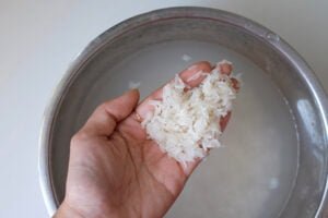 خیساندن برنج قبل آبکش برای تهیه عدس پلو مجلسی