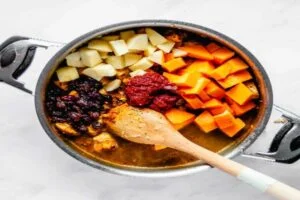 اضافه کردن تکه‌های مرغ، ذغال‌اخته، کدو و سیب خردشده در تهیه خورش کدوحلوایی