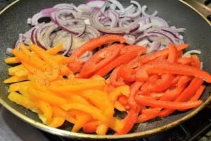 تفت دادن پیاز، فلفل دلمه ای و سیر برای خورش کدو حلوایی با مرغ و لوبیا سبز