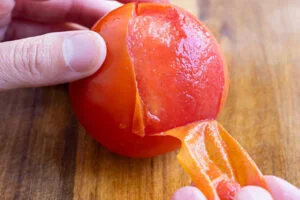 پوست کندن گوجه برای تهیه میرزا قاسمی با کشک