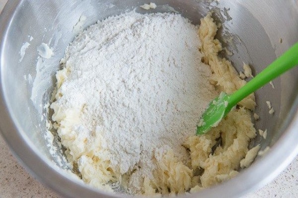 اضافه کردن آرد به مخلوط مواد تهیه شیرینی اسکار گردویی