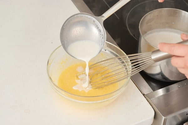 مخلوط کردن شکر، تخم‌مرغ، شیر و وامیل برای تهیه کیک هندوانه یلدایی