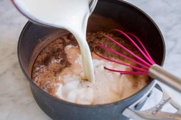 مخلوط کردن مواد برای تهیه سس شکلاتی روی کیک خیس بدون شیر