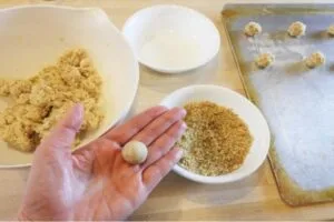 غلتاندن گلولهای خمیری سیرینی اسکار در گردوهای خردشده