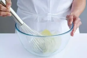 زدن سفیده تخم مرغ برای غلتاندن شیرینی های اسکار در آن