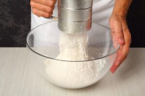 آماده کردن آرد در طرز تهیه شیرینی پنجره ای بدون قالب