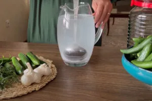 آماده کردن مخلوط سرکه، نمک و آب برای تهیه خیارشور دبه ای