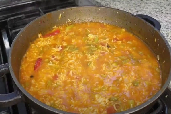 لایه‌گذاری برنج و مخلوط گوجه با لوبیا سبز در قابلمه برای دم کشیدن