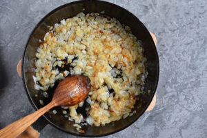 تفت دادن سیر و پیاز برای تهیه مرغ شکم پر مجلسی