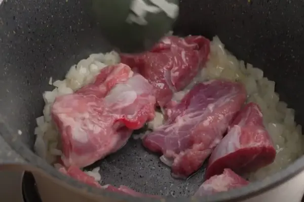 تفت دادن پیاز و گوشت برای تهیه خورشت کنگر مجلسی
