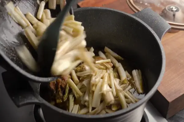 اضافه کردن کنگر و سبزی به گوشت برای تهیه خورشت کنگر مجلسی