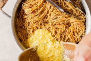 افزودن سس تخم مرغ و پنیر گودا به ماکارونی و بیکن سرخ شده