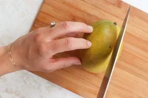 اقدام به برش زدن انبه زرد برای تهیه ترشی انبه