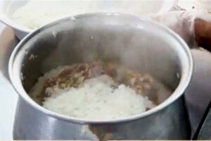 ریختن برنج روی گوشت در قابلمه در تهیه ته‌چین گرمساری