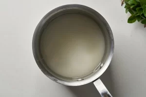 حرارت دادن به ترکیب آب و شکر برای تهیه شربت نعنا
