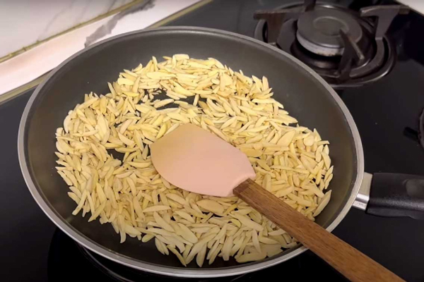 تفت دادن خلال بادام و خلال پسته در طرز تهیه شیرین پلو با مرغ ریش ریش