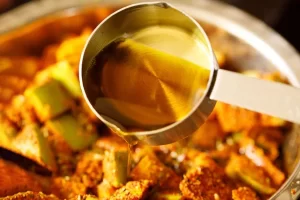 افزودن روغن خردل به مواد ترشی انبه پاکستانی