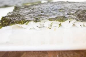 برگرداندن نوار جلبک و برنج در تهیه سوشی مرغ