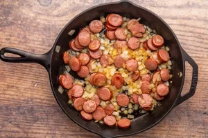 سرخ کردن سوسیس پپرونی برای تهیه سالاد پپرونی بدون پاستا