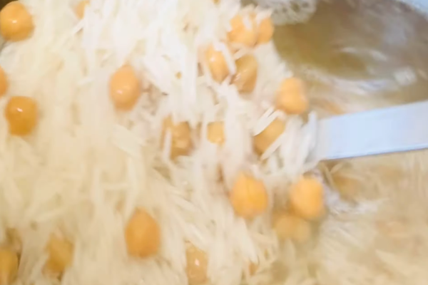  افزودن نخود به برنج در حال جوش در تهیه نخودپلو با کشمش