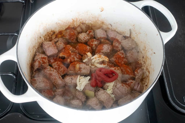 افزودن ادویه به گوشت و پیاز تفت داده شده در تهیه خورشت بامیه دونفره
