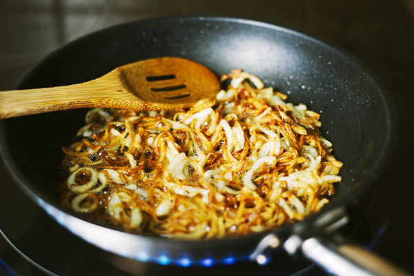 تفت دادن پیاز و سیر در تهیه پیازداغ عدسی رستورانی