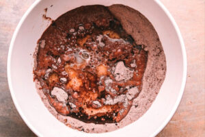 اضافه کردن تخم مرغ، شیر، روغن و وانیل در تهیه کیک خیس شکلاتی کافی شاپی
