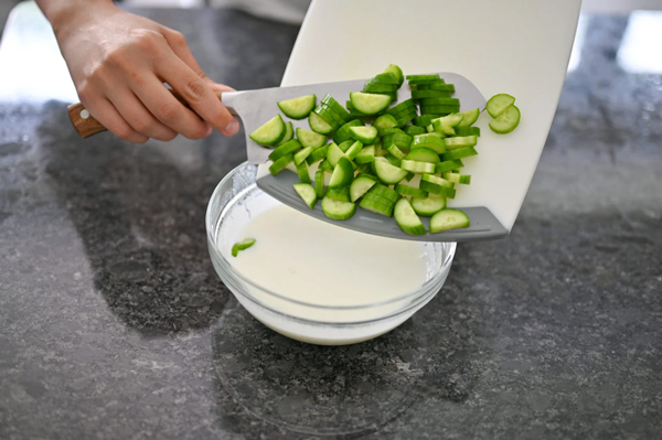 اضافه کردن خیار خردشده به ماست در تهیه ماست و خیار
