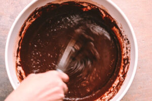 مخلوط کردن تخم مرغ، شیر، روغن و وانیل در تهیه کیک خیس شکلاتی کافی شاپی