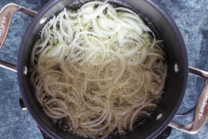 سرخ کردن پیاز در قابلمه برای آماده سازی خورشت بادمجان با بامیه