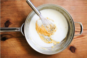 اضافه کردن شیر به مخلوط کره و آرد در تهیه سس بشامل