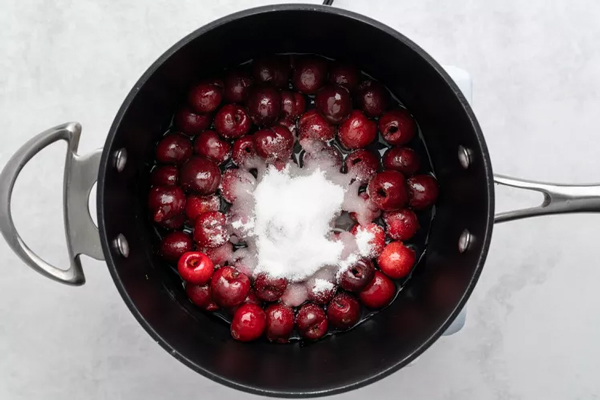 اضافه کردن شکر و آبلیمو برای تهیه سس گیلاس به قابلمه