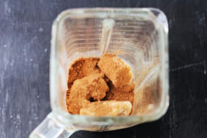 اضافه کردن پودر کاکائو به موز یخ زده برای تهیه میلک شیک موز و شکلات