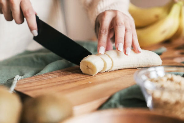 خرد کردن موز با چاقو برای تهیه میلک شیک موز و نسکافه