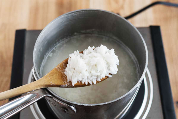 آبکش کردن برنج و کفگیر چوبی برای تهیه ته چین مرغ و بادمجان