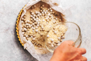 ریختن حبوبات و برنج خام روی کاغذ روغنی خمیر تارت