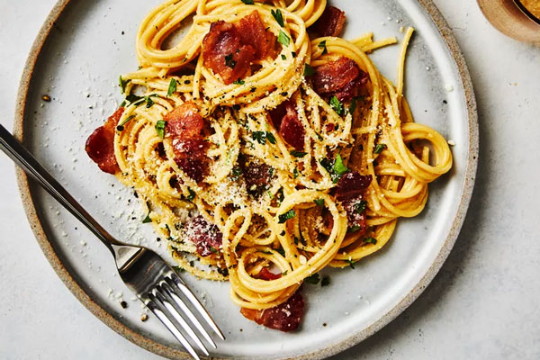 سرو اسپاگتی کاربونارا با تزیین پنیر و سبزی تازه 